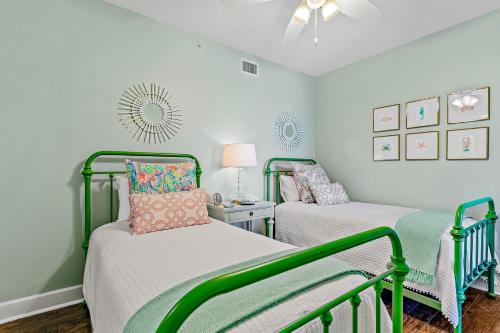 two beds in a room with white walls and green accents at The Preserve 202 in Blue Mountain Beach