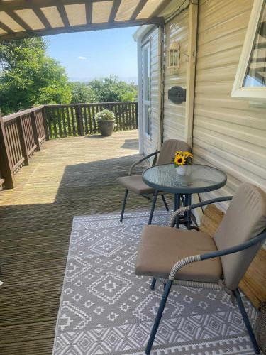 a patio with two chairs and a table on a porch at Cosy Caravan Ty Newydd in Brynteg