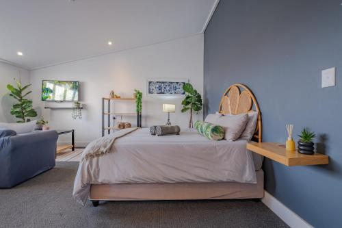 a bedroom with a bed and a blue wall at Hermanus Waterfront Boho Studio Apartment, Whale Coast Hideaway in Hermanus