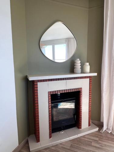a living room with a fireplace with a mirror at La Terrasse de L Anse Maison avec Vue Mer et Spa Extérieur in Fermanville