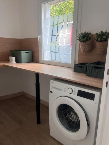 a laundry room with a washing machine under a counter at La Terrasse de L Anse Maison avec Vue Mer et Spa Extérieur in Fermanville