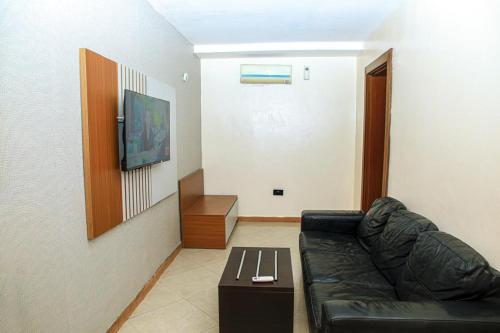 a living room with a black leather couch and a table at Villa Toscana Victoria Island Lagos in Lagos