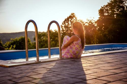 a little girl in a dress sitting next to a pool at Sky Resort 