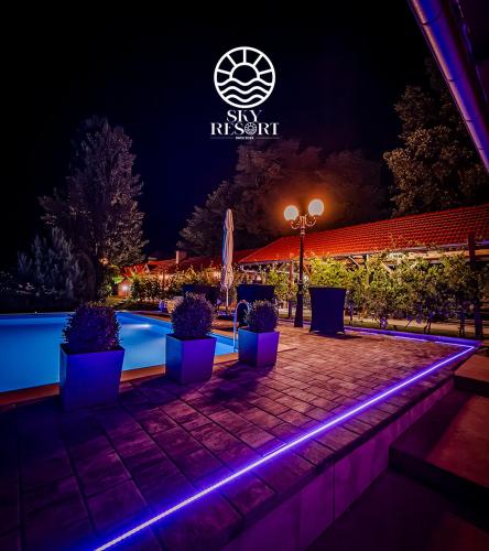 a night view of a swimming pool with a lit up sign at Sky Resort in Gunjavci