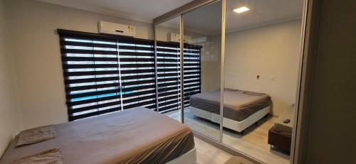 マリンガにあるCasa luxo, 3 suítes, ar 3 qtos, Jardim Espanha!のベッドと大きな窓のある寝室