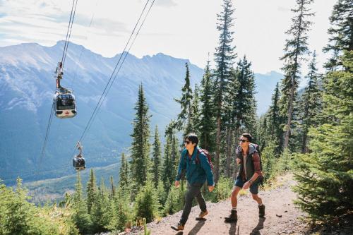 two men walking on a mountain trail with a ski lift at Rimrock Banff, Emblems Collection in Banff