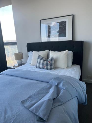 un letto con lenzuola e cuscini blu in una camera da letto di One bedroom with Spacious n Amazing water view apartment a Melbourne
