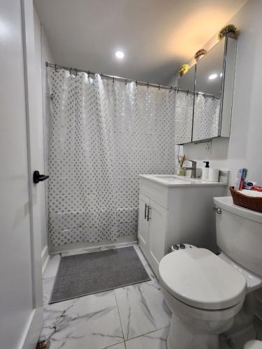 a white bathroom with a toilet and a shower at Entire 2BR Apt in Midtown Toronto, walk to Subway & Shops in Toronto