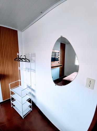 a mirror in a white room with a shelf at Suíte Nosso Abrigo - Jaguaribe 2km do Capivari in Campos do Jordão