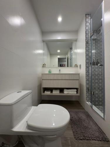 a white bathroom with a toilet and a shower at Departamento 1BD con AC y terraza en el centro de Barranco in Lima