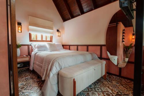 a bedroom with a bed and a bench in it at Casa da Ilha - Hotel Fazenda Gabro in Apiaí