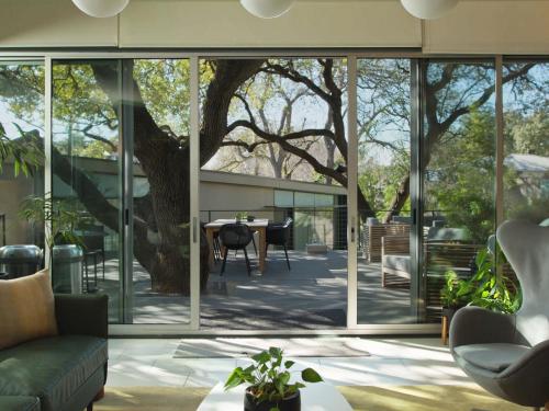 a living room with large glass windows and a tree at Frame Hotel - Treehouse in Austin