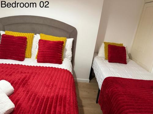 a bedroom with two beds with red and yellow pillows at 5 Brunswick St - Bedroom 02 downstairs in Bristol