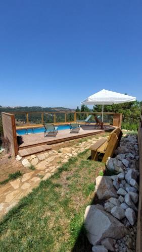 a swimming pool with benches and an umbrella at Casa de Cima - Sítio dos Henriques in Alfeizerão