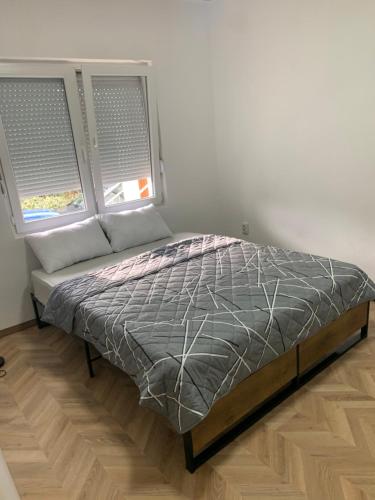 a bed sitting in a room with two windows at Zakovski in Skopje