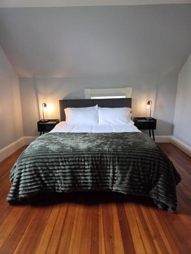a bed with a black comforter and two side tables at The Leverett House in Keene