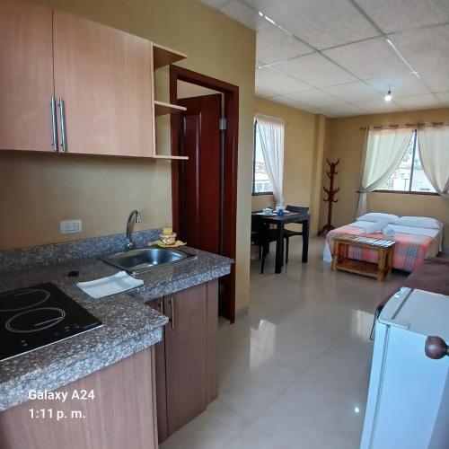 a kitchen with a sink and a living room at Suites Sonikikos in Ballenita