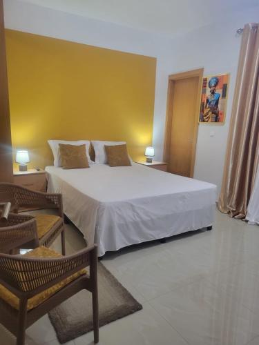 a bedroom with a white bed and a yellow wall at Maison Mima in Tarrafal