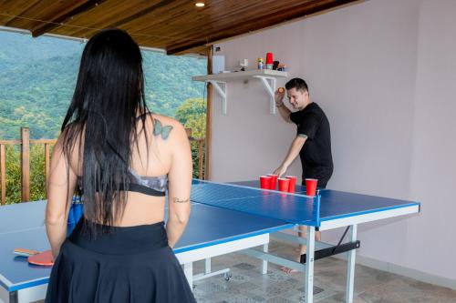 a man standing at a ping pong table with a woman at Cabaña de lujo en la montaña in Santa Marta