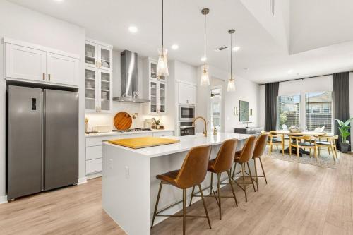 a kitchen with white cabinets and a large island with bar chairs at Modern Austin Escape with Pool and BBQ in Austin