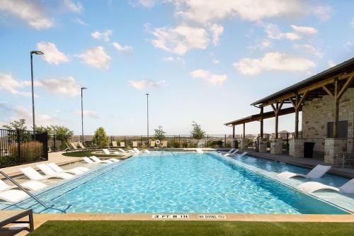 a large swimming pool with lounge chairs and a building at Modern Austin Escape with Pool and BBQ in Austin