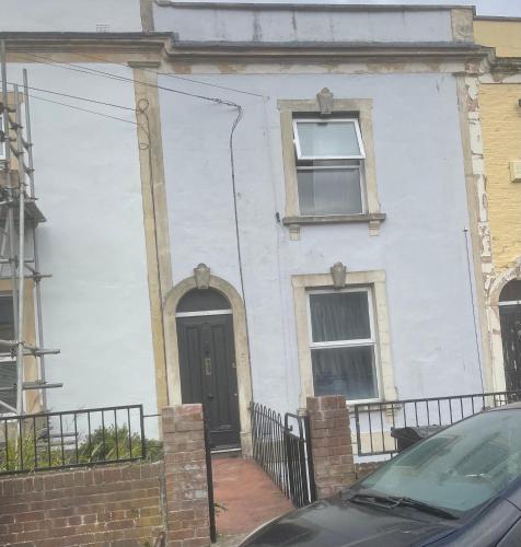 a white house with a black door and windows at 5 Brunswick St - Bedroom 02 downstairs in Bristol