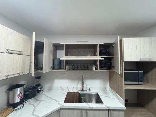une cuisine avec des armoires blanches et un évier dans l'établissement Casa Viveo, a modern and spacious house!, à San José
