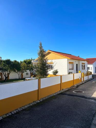 a yellow and white fence next to a street at Ninho da Irene in Vieira de Leiria