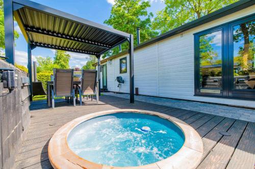 a hot tub on a wooden deck next to a house at 4pers Welness vakantiehuis in natuurrijke omgeving in Reutum