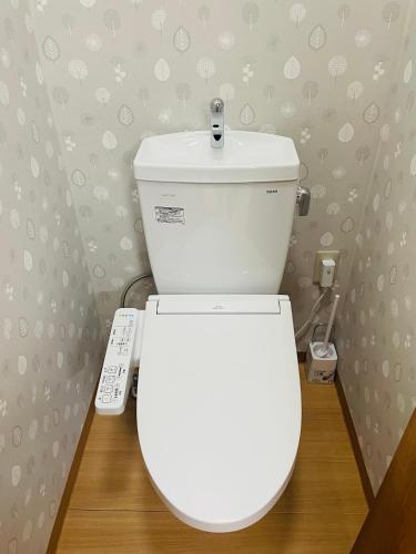 a white toilet in a bathroom with a remote control at KeiCo 定員12名 駐車場12台 露天風4分 河口湖6分 富士急10分 ふじてんスノーリゾート10分 in Narusawa