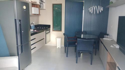 Una cocina con mesa y sillas y un refrigerador. en Paraíso em Tamandaré - Maui Beach, en Tamandaré
