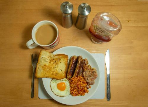 a plate of breakfast food with eggs beans and a cup of coffee at Taj Executive Hotel Islamabad - Luxury Stays Opposite Jinnah Super F-7 in Islamabad