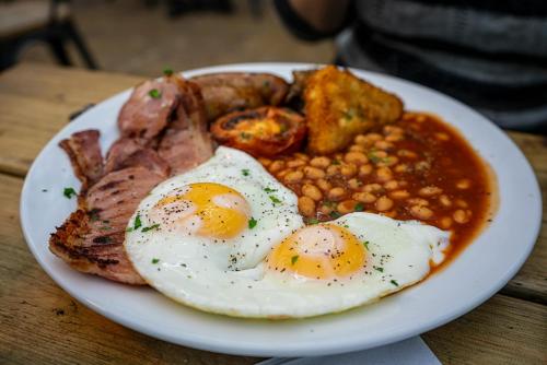 a plate of eggs and bacon and beans on a table at Taj Executive Hotel Islamabad - Luxury Stays Opposite Jinnah Super F-7 in Islamabad