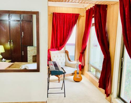 Un dormitorio con cortinas rojas y una silla y un espejo. en 3 Bed Luxury House with Valley Views & Privacy, en Murree