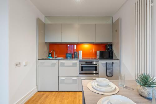 a kitchen with white cabinets and a table with plates at Stylish City Centre 1-Bed Apt - Balcony - Sleeps 5 in Leicester