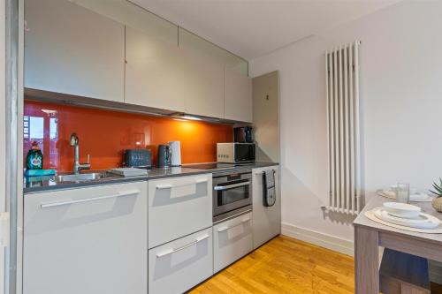 a kitchen with white cabinets and an orange wall at Stylish City Centre 1-Bed Apt - Balcony - Sleeps 5 in Leicester