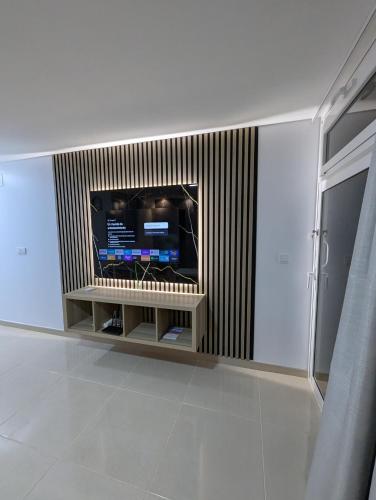 a living room with a television on a wall at Apartamentos Anau k & L- Playa del inglés - Yumbo in Playa del Ingles