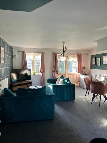 a living room with two blue couches and a television at The Residency 4 bed home in Liverpool free parking in Litherland