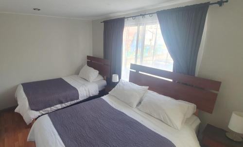zwei Betten in einem Hotelzimmer mit Fenster in der Unterkunft Hostal del Rio in Concepción