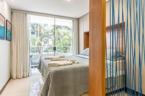 a bedroom with a bed and a large window at Flat Aconchegante c/ Piscina em Carneiros - FH105 in Tamandaré