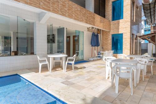 a patio with tables and chairs next to a pool at Flat Aconchegante c/ Piscina em Carneiros - FH105 in Tamandaré