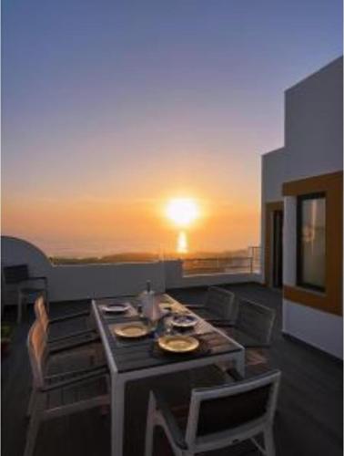a living room with a table and chairs and the sunset at Ericeira penthouse with total sea view in Ericeira