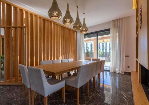 a dining room with a wooden table and chairs at Villa Palma 7 chambres in Marrakech