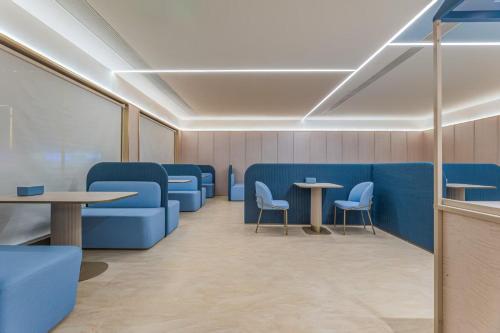 a waiting room with blue chairs and tables at Hanting Huangshan Scenic Area South Gate Xiaoyaoxi Transfer Center in Huangshan