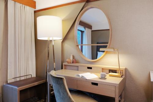 a room with a desk with a mirror and a lamp at Alyeska Resort in Girdwood