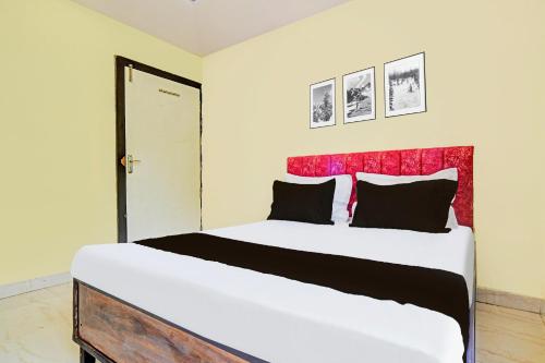a bedroom with a large white bed with a red headboard at Hotel O Paradise Green in Indore