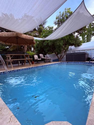 a large blue swimming pool with a white canopy at Izzy Room - Ferdie's Place in Port Antonio