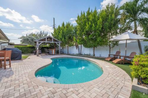 a swimming pool in a backyard with a table and chairs at Heated Pool Villa-Walk to Beach-Tiki Bar-Sleeps 8 in Pompano Beach