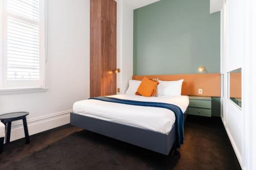a small bedroom with a bed with orange pillows at Middle Park Hotel in Melbourne