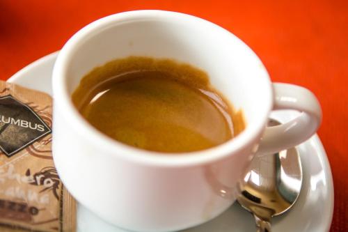 a cup of coffee on a plate with a spoon at Hotel della Vittoria in Ancona